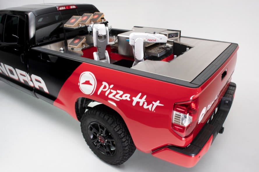 a red and black pickup truck with a pizza kitchen in the back